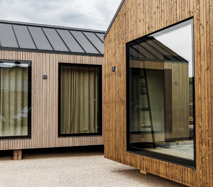 Timber-clad cabins with a standing seam roof and full-height windows